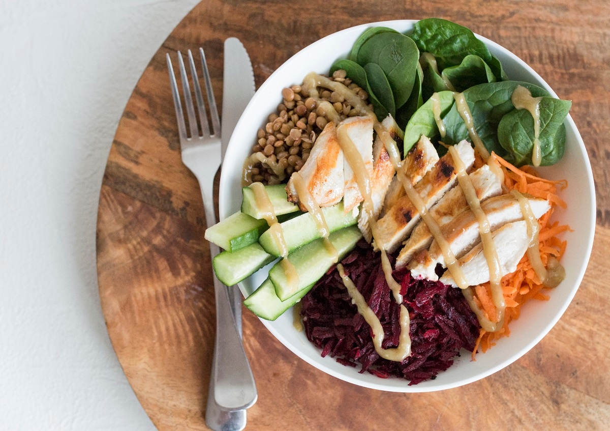 A delicious bowl of food featuring tender chicken, fresh vegetables, and a flavorful dressing.