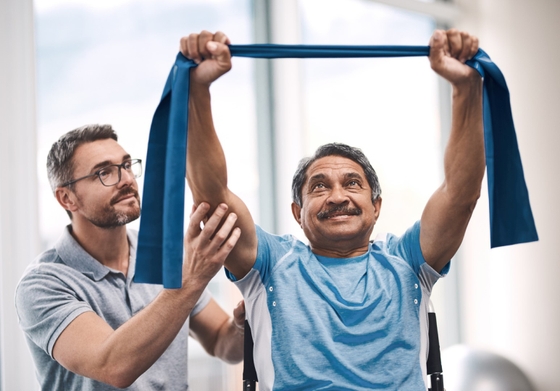 A physical therapist assisting a man doing exercises.