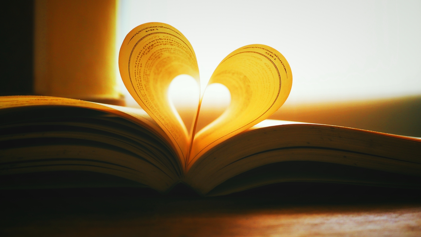 An open book, with two pages curled together to form a heart shape