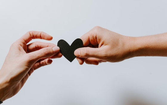 man and woman holding a black heart