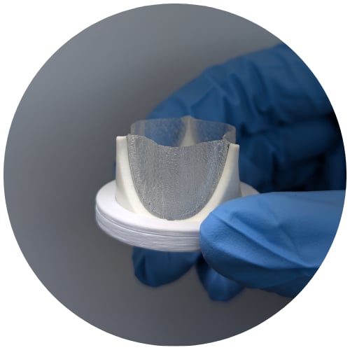 Gloved hands holding a small medical device prototype