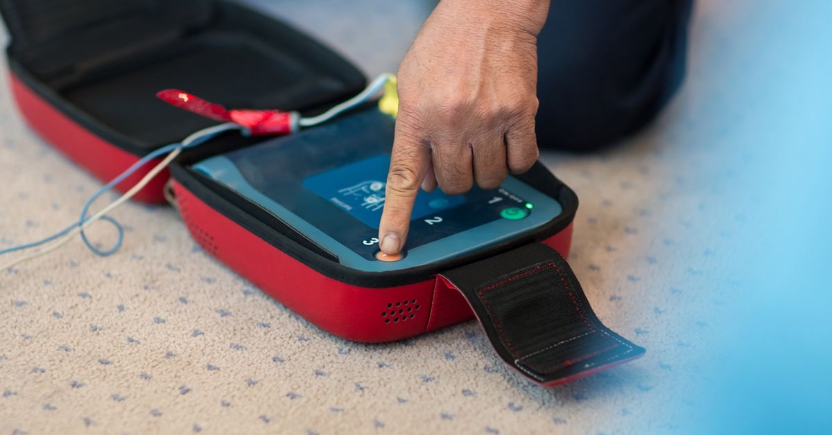 A person pressing the buttons on the automated electronic defibrillator