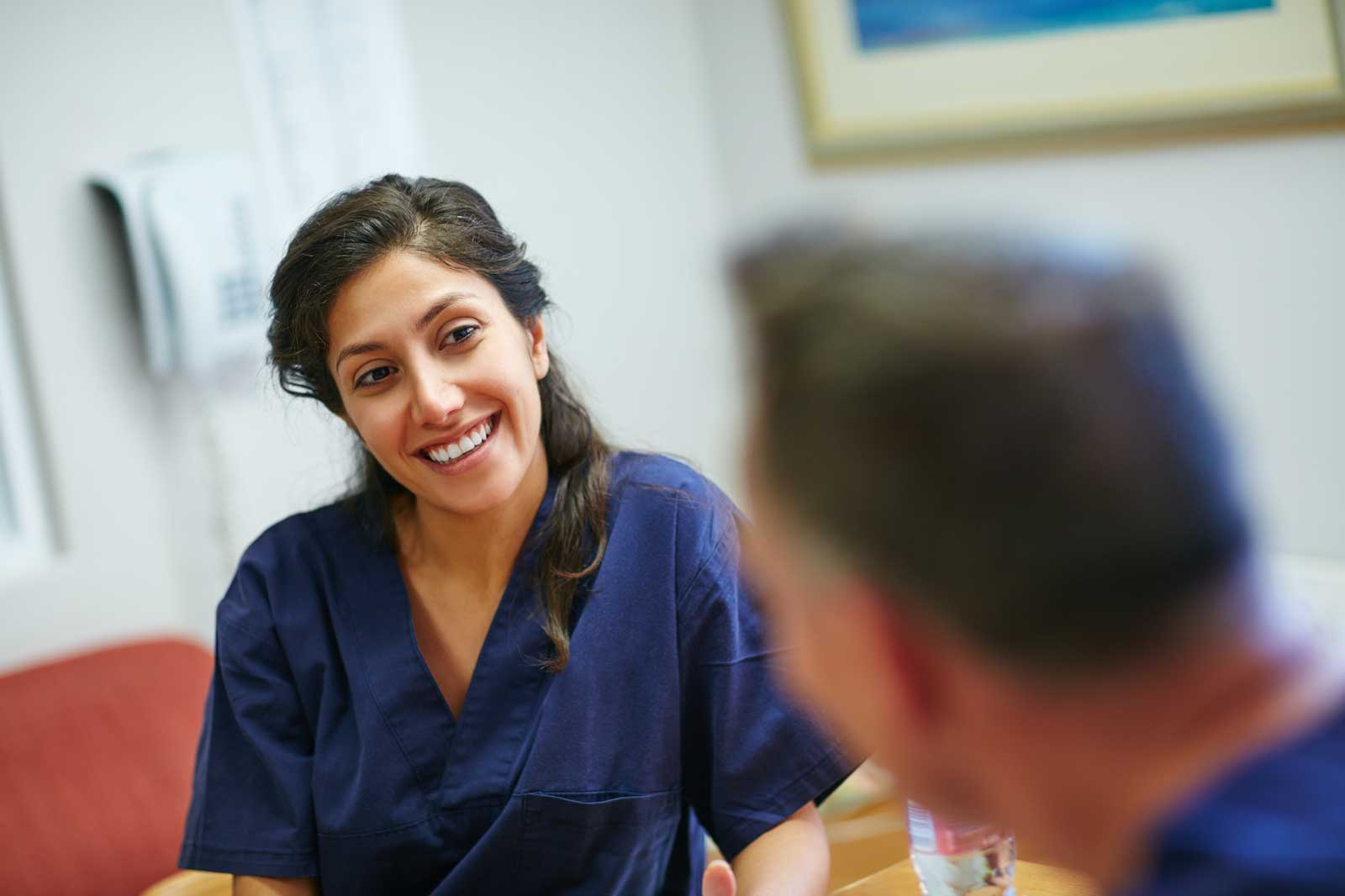 Female health professional smiling, wearing blue scrubs