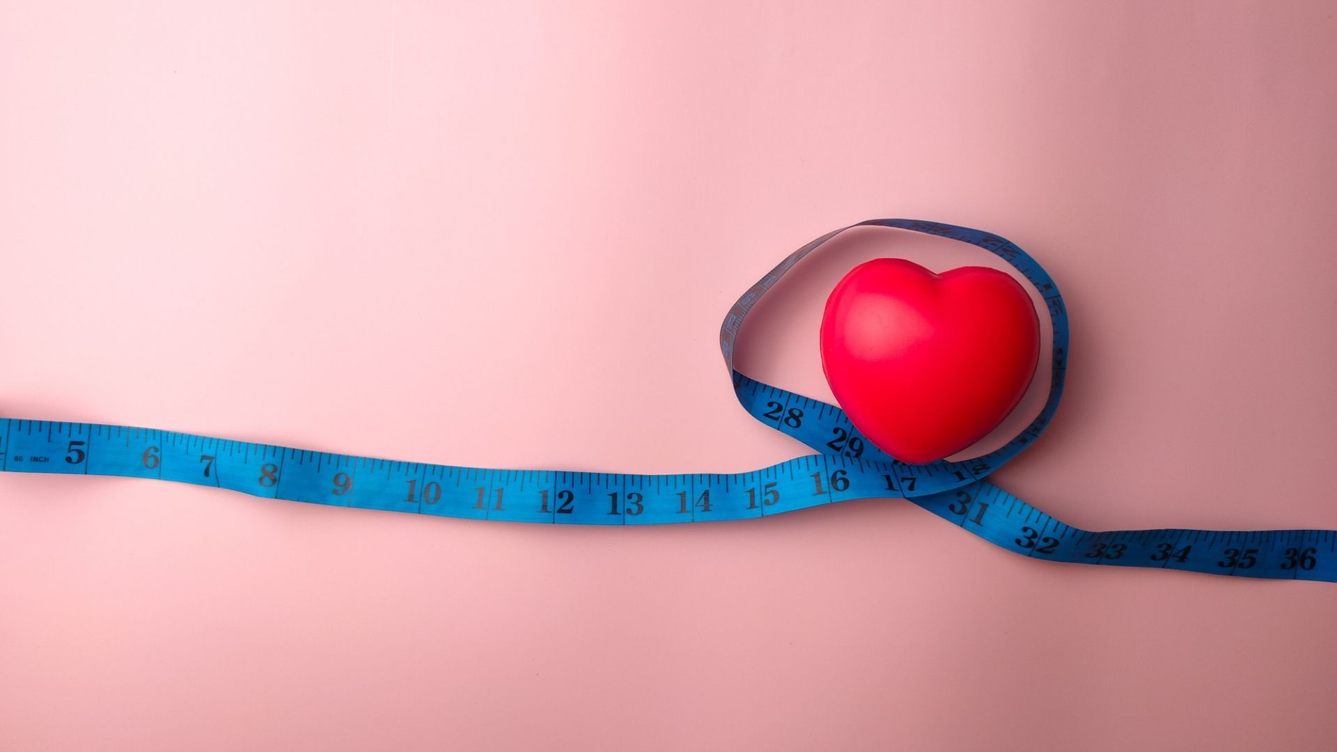  Measuring tape with heart shape on a pink background. Medical and health concept.