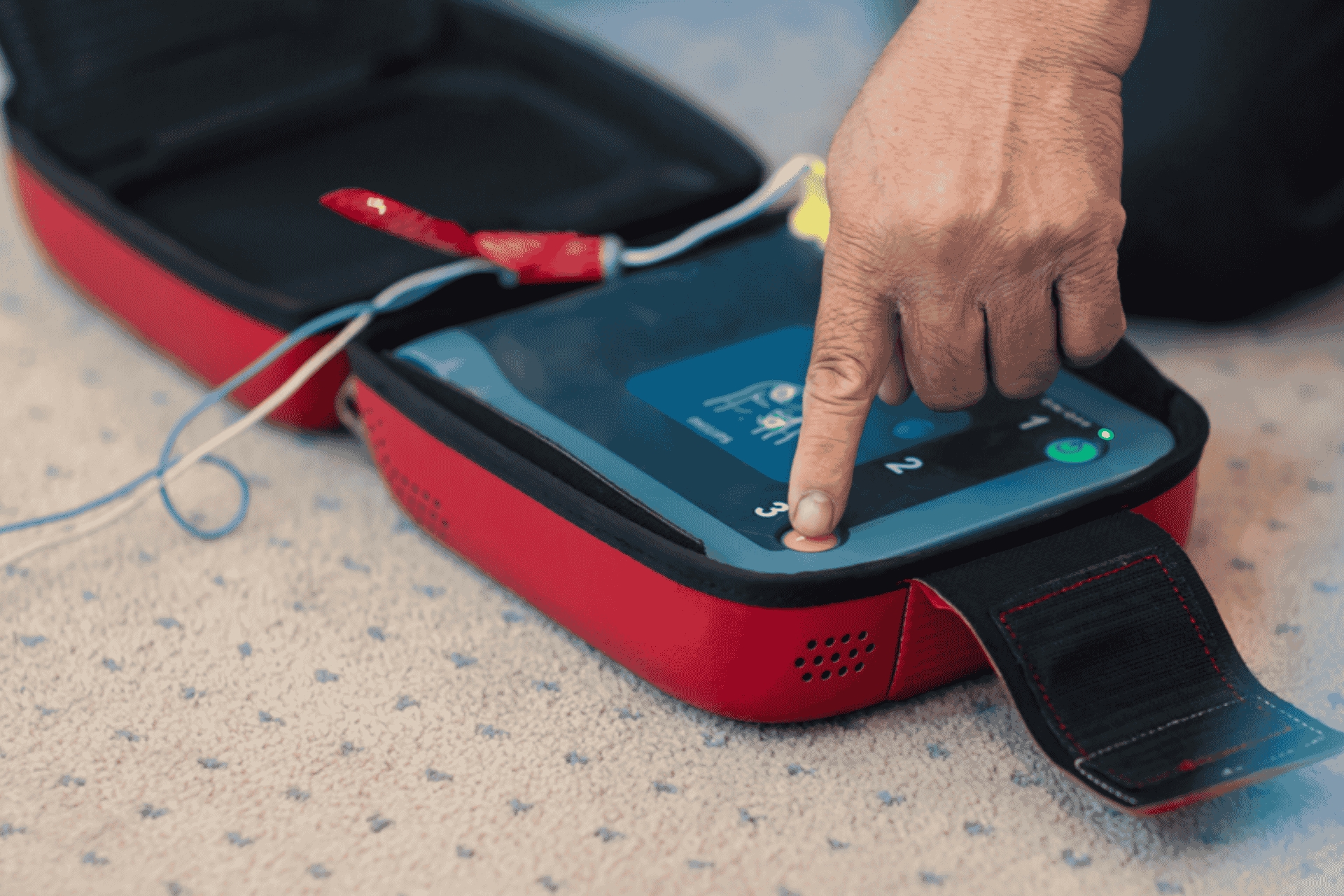 A person pressing the buttons on an AED (automated electronic defibrillator)