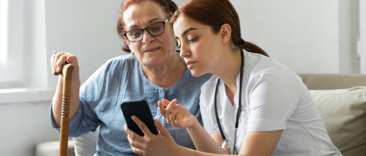 A doctor talking to her older patient while looking at a phone