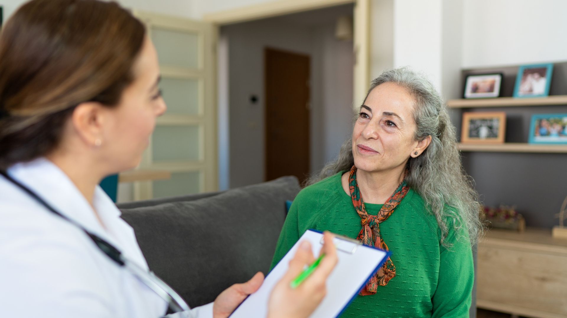 Female researcher examining her senior patient at home