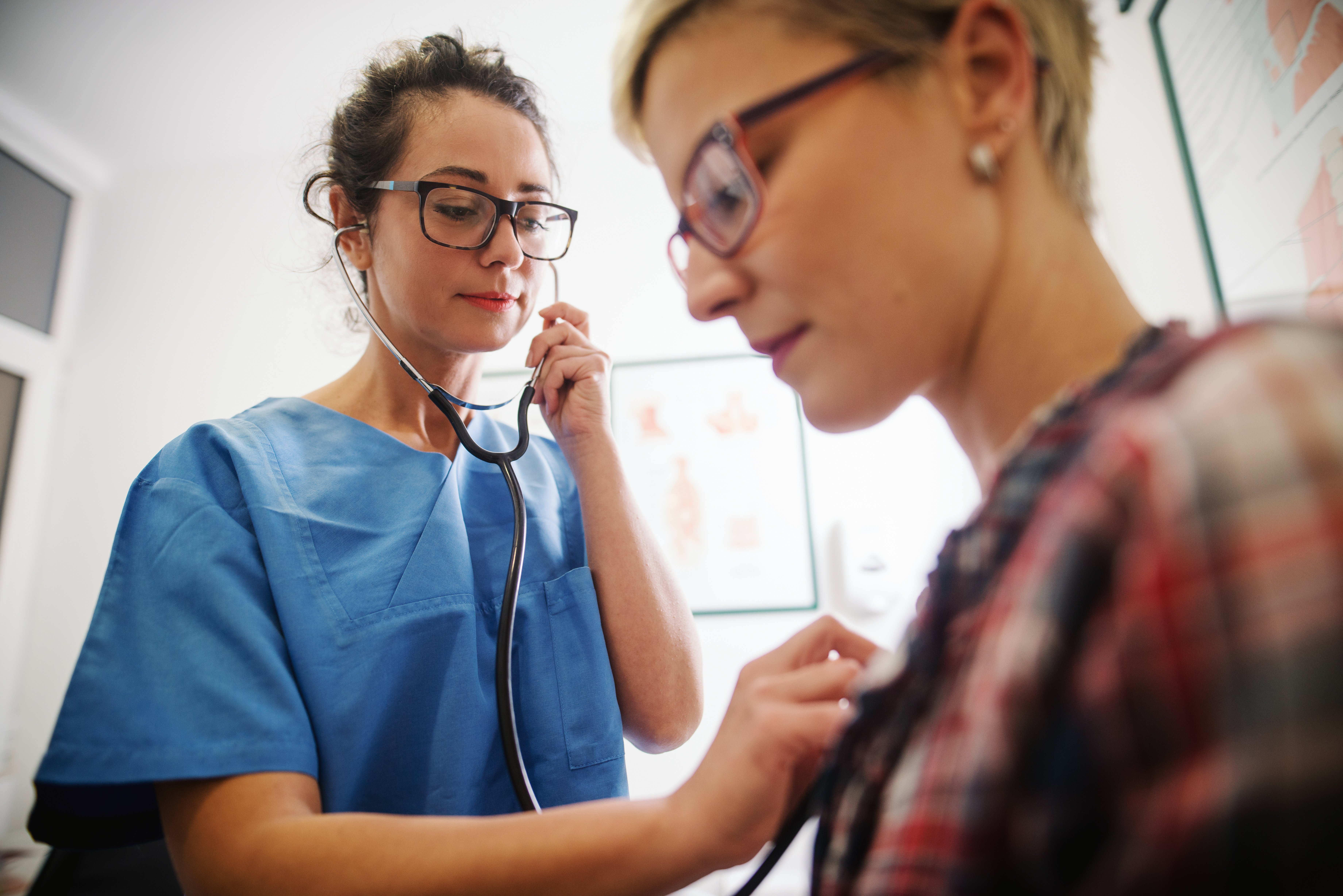 A nurse using a stethoscope on a patient to check her heart