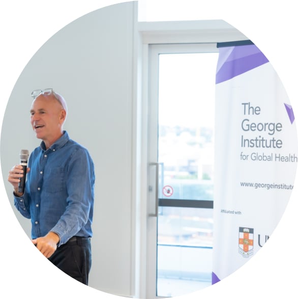 Bruce Neal presenting at a podium beside a George Institute for Global Health banner