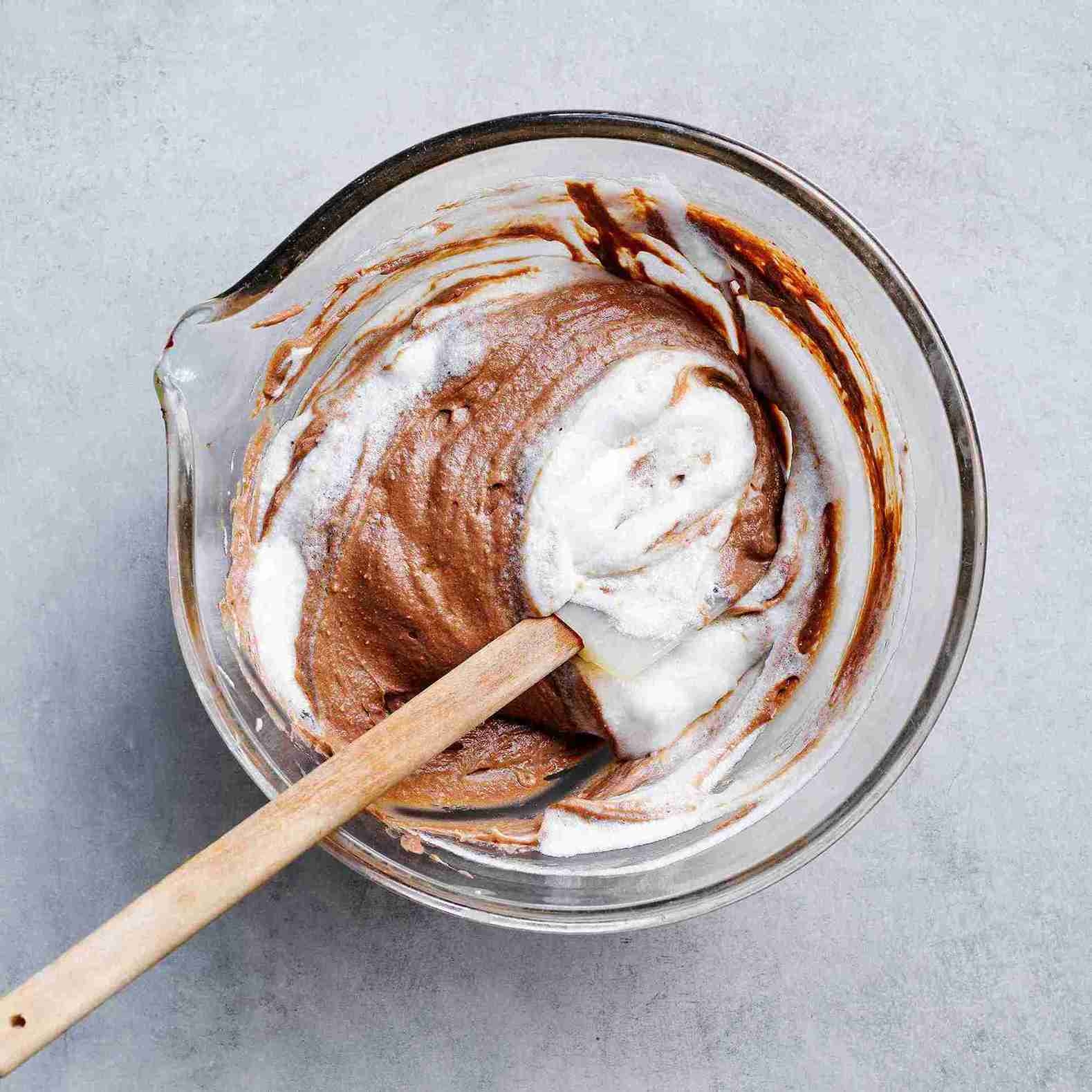 egg whites being gently folded into chocolate mixture in batches