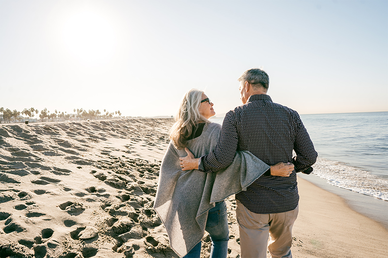 An elderly couple strolling along the sandy beach, enjoying a peaceful walk by the ocean's edge.
