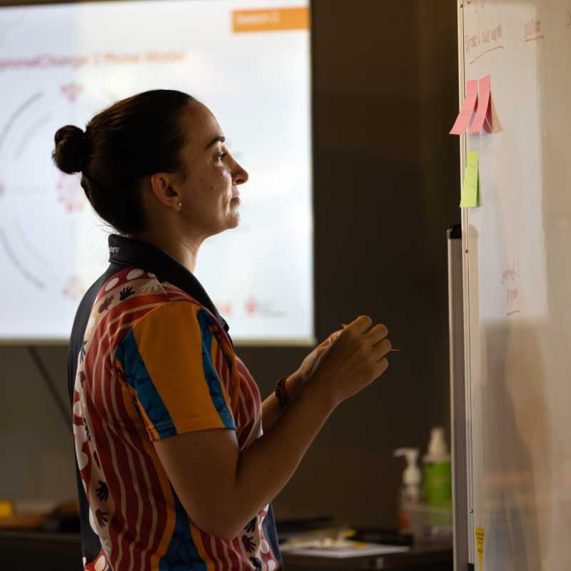 A Heart Foundation staff member putting post-it notes on a whiteboard