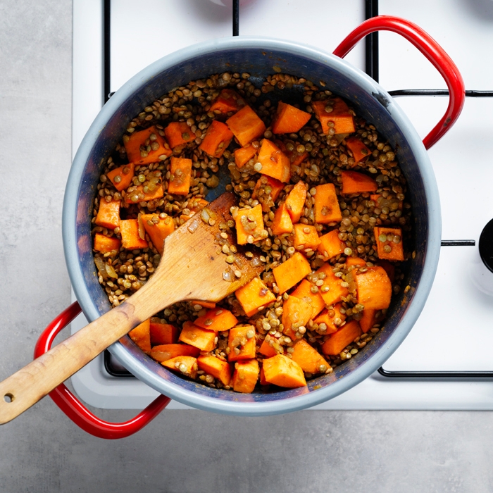 Sweet potato and lentils cooking in the same pan as the onion and curry paste