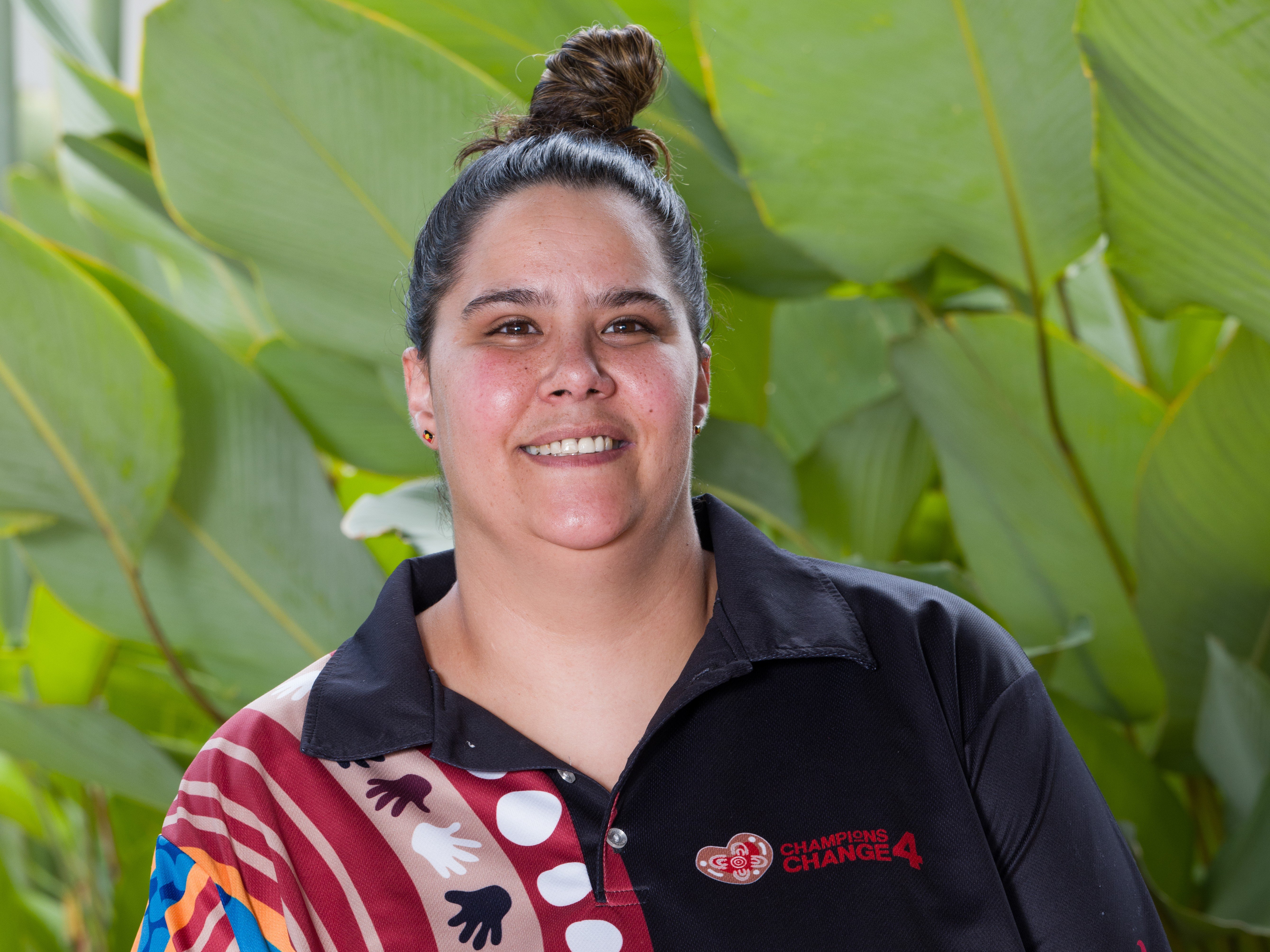 Person wearing a black and patterned polo shirt with the Champions 4 Change logo