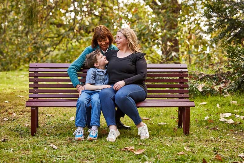 Grandma, mum and a young boy sitting in a park