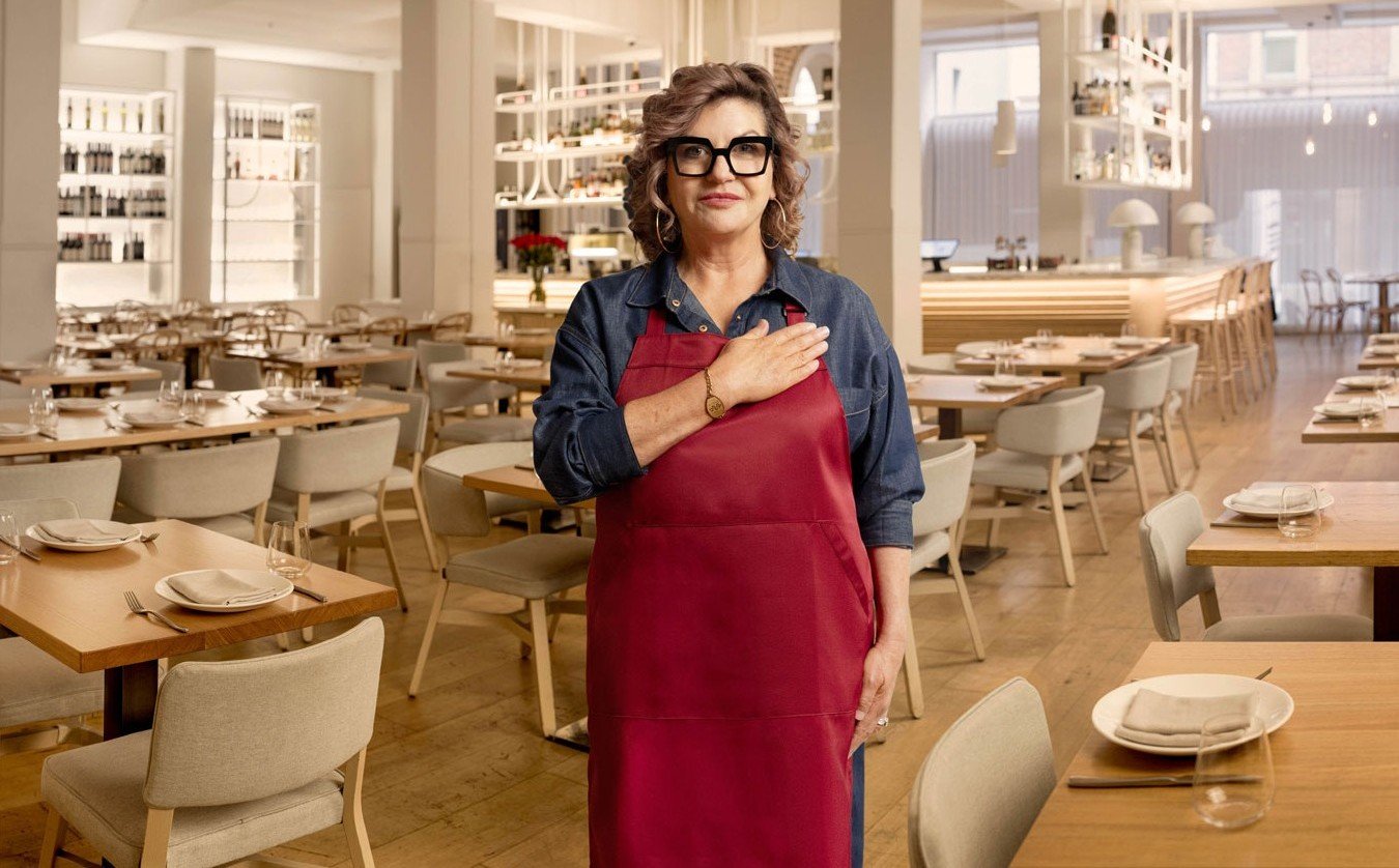 Mandy Hall in a restaurant with hand on heart