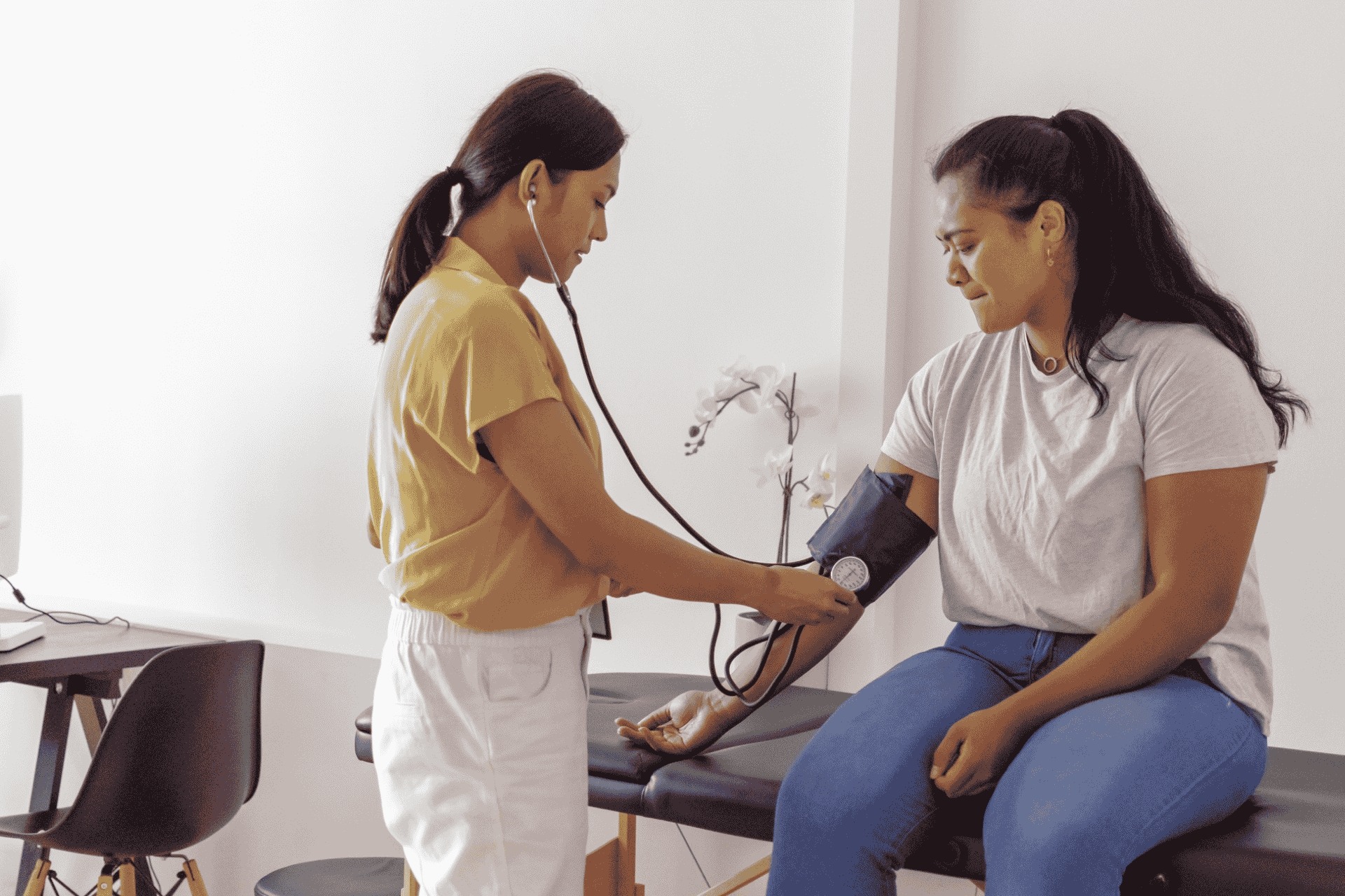 Young woman of Pacific Islander descent at risk of cardiovasular disease having blood pressure measured by doctor at routine medical appointment.