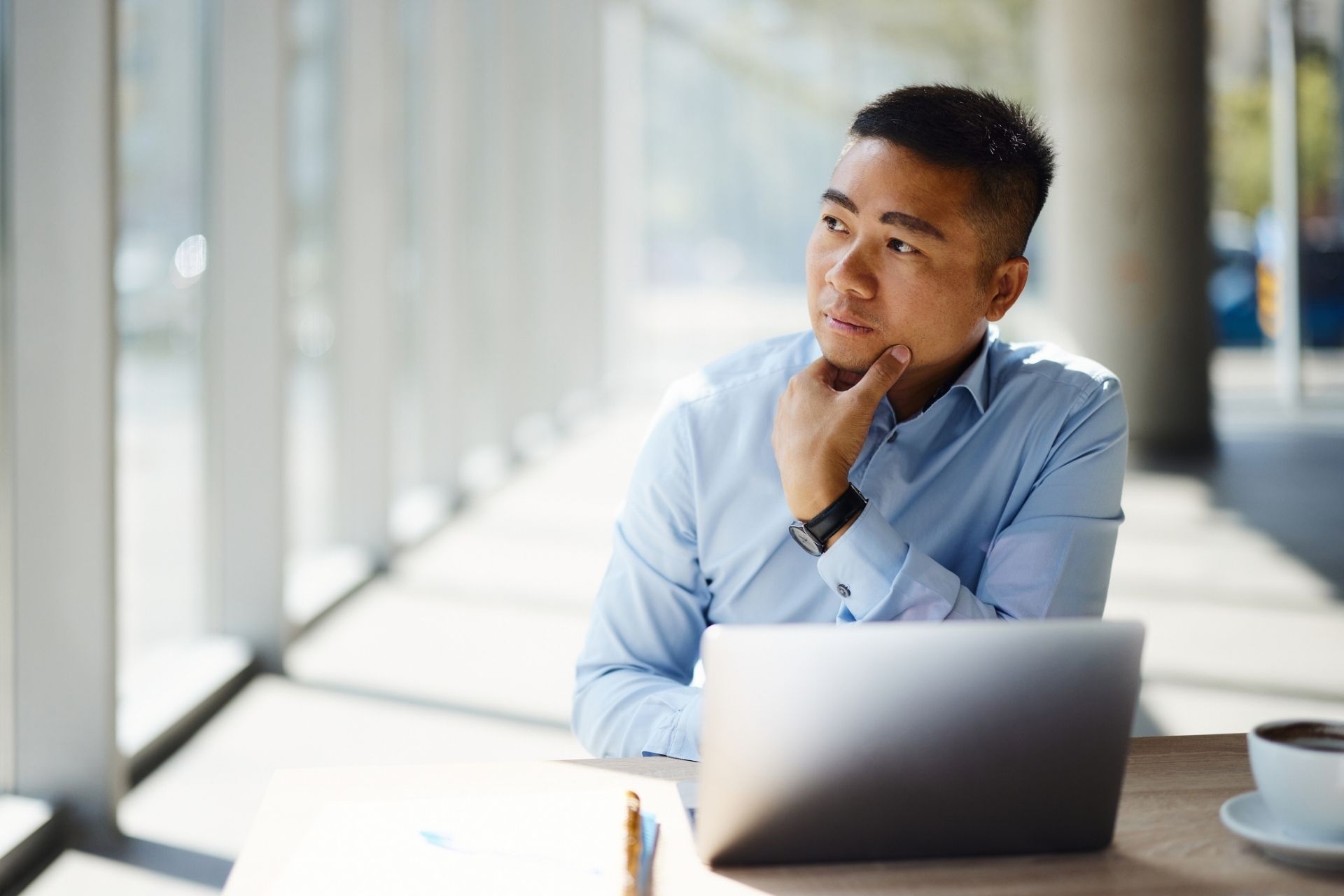 Pensive Asian researcher working on laptop in the office