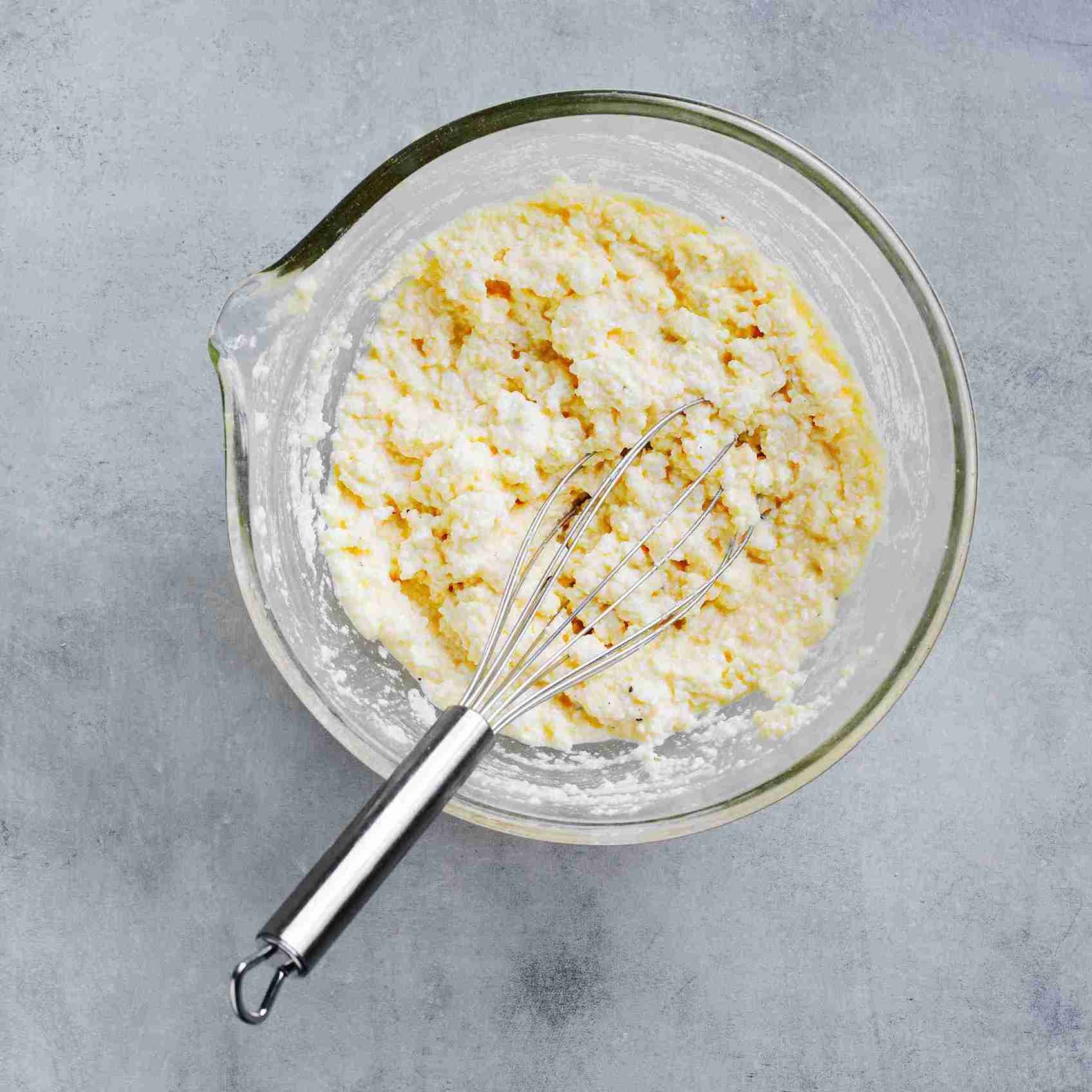 ricotta, eggs, and parmesan being whisked together in a mixing bowl