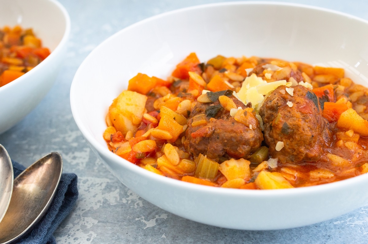 Two bowls of hearty stew filled with savory meatballs and a medley of colorful vegetables.