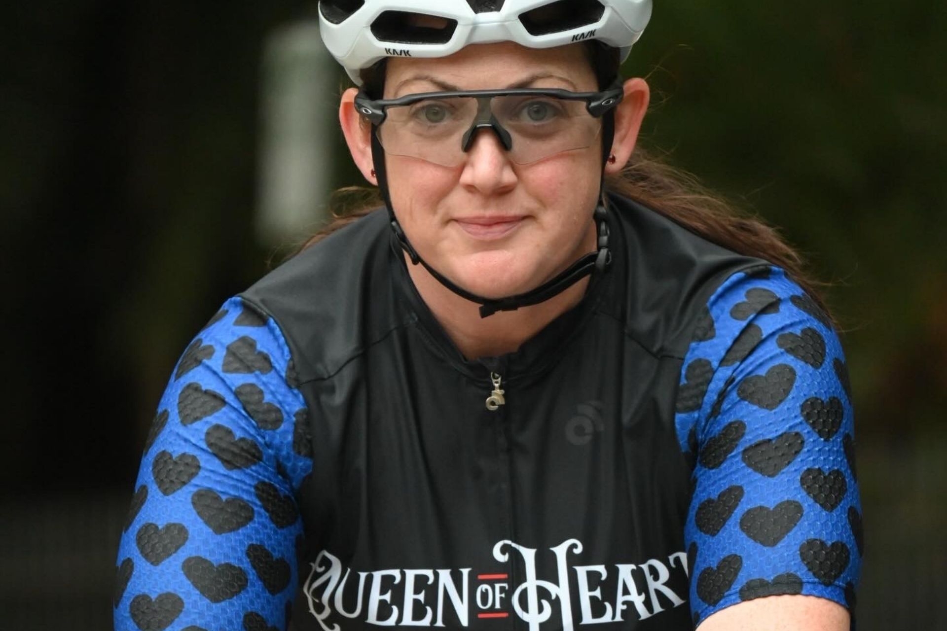 A woman, Dawn Beaumont, riding her bike with a biking suit that reads 'Queen of Hearts'