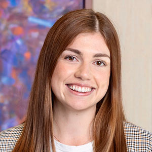 Dr. Eden Barrett smiling with long light brown hair and wearing a checked jacket