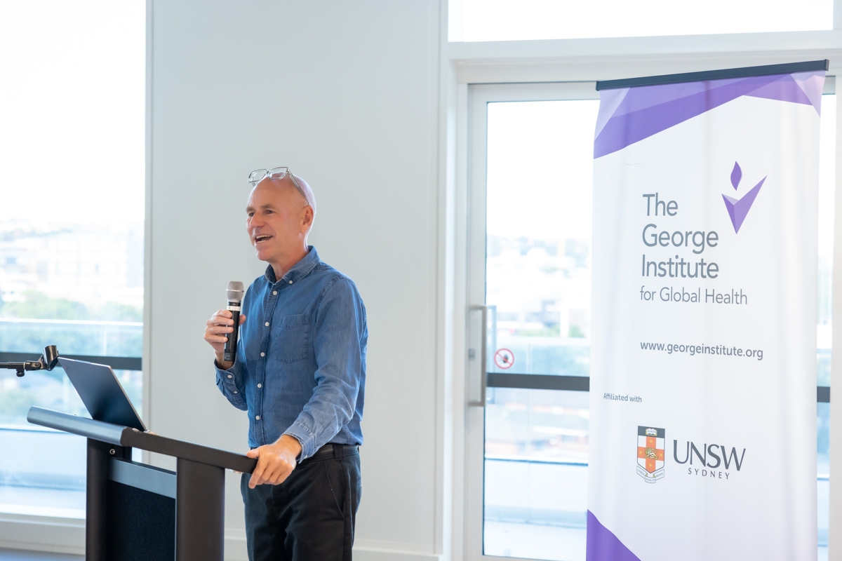 Bruce Neal presenting at a podium beside a George Institute for Global Health banner