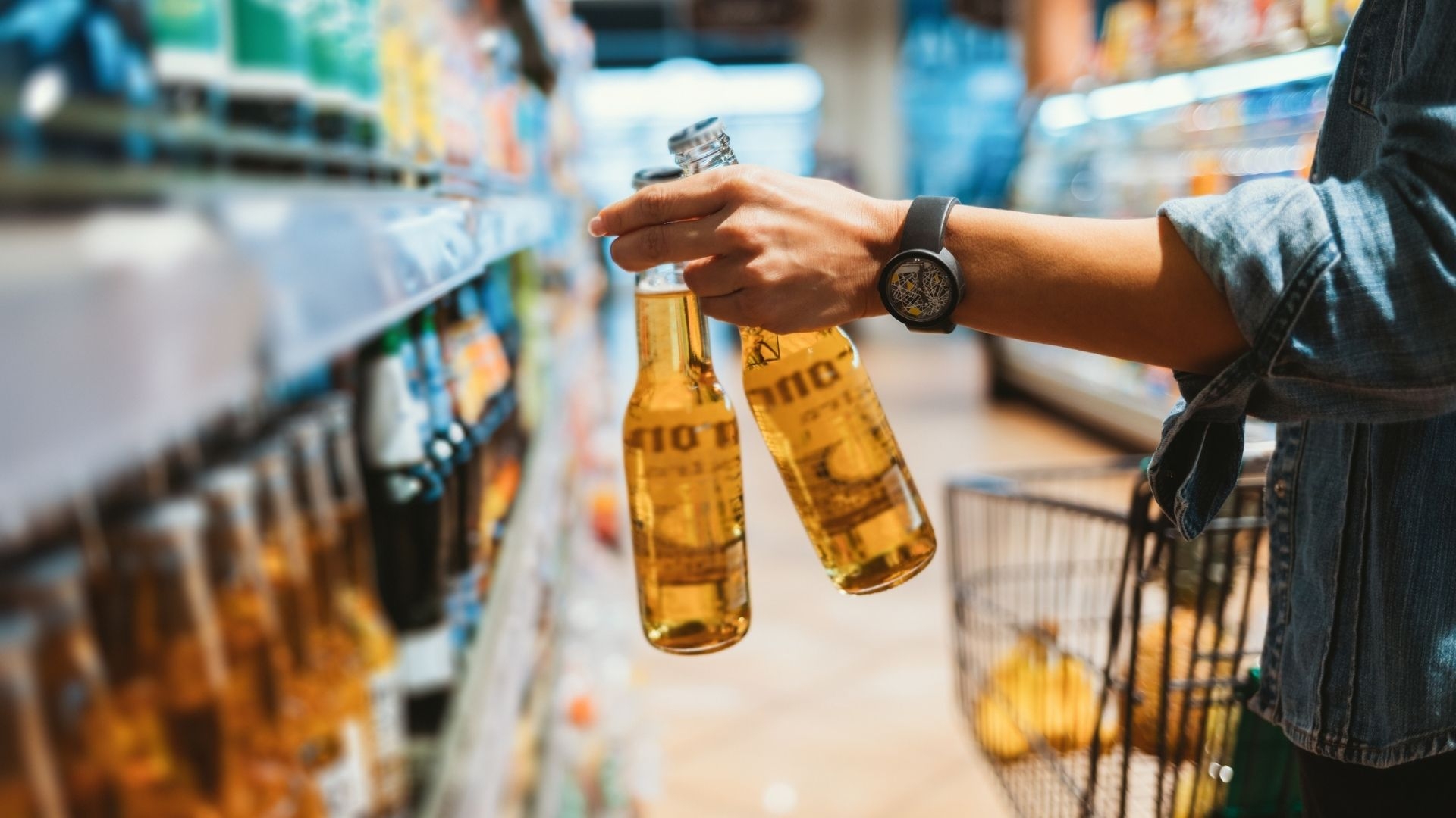 Close-up of female hand holding two glass bottle with alcoholic drink in store