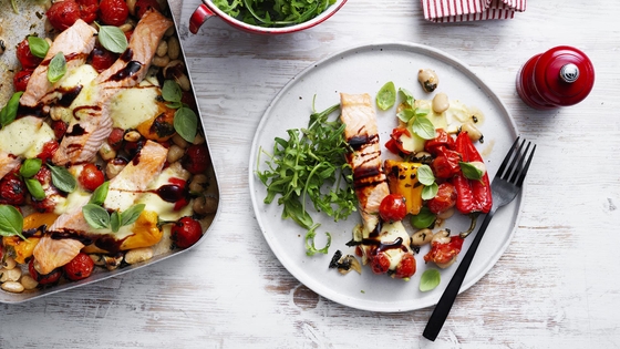 A baking dish and a plate, each containing the One pan salmon caprese bake, is arranged on a table