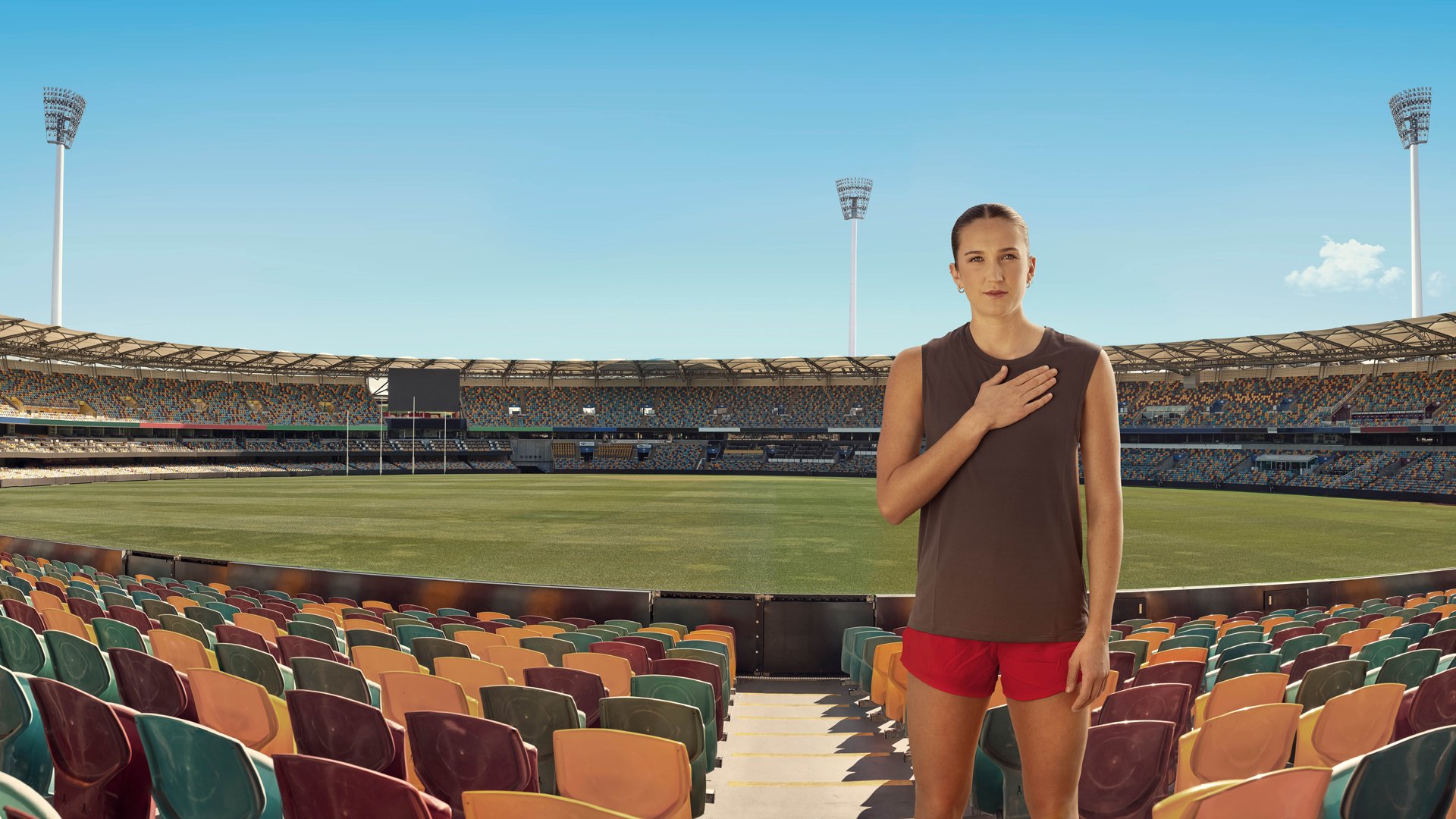 AFLW's rising star Tay Smith standing in an empty Gabba stadium with her hand on her heart.