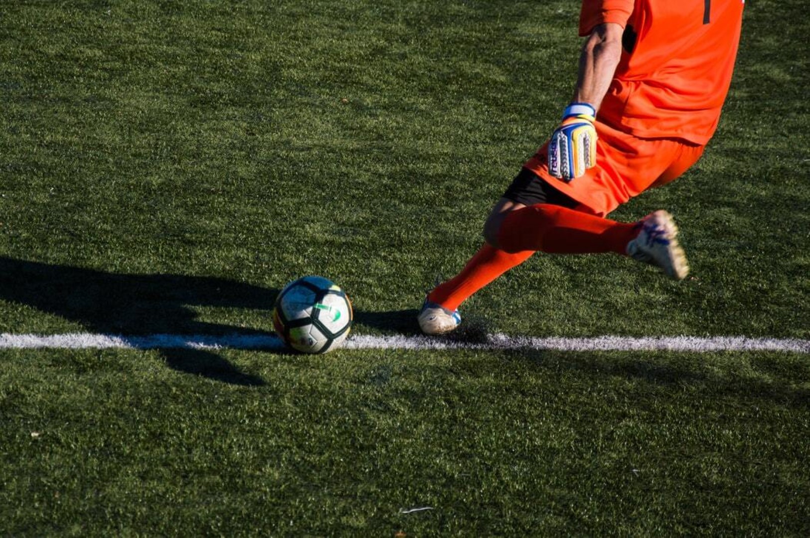 A soccer player kicking a soccer ball on a field, displaying skill and precision in the game.