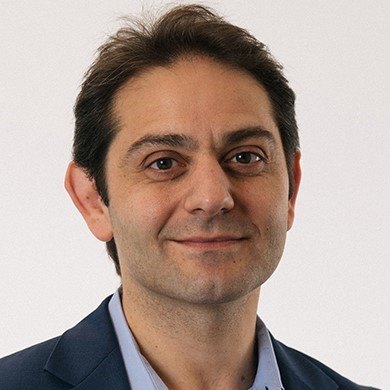Associate Professor Peter Psaltis in a suit and tie, smiling confidently at the camera.