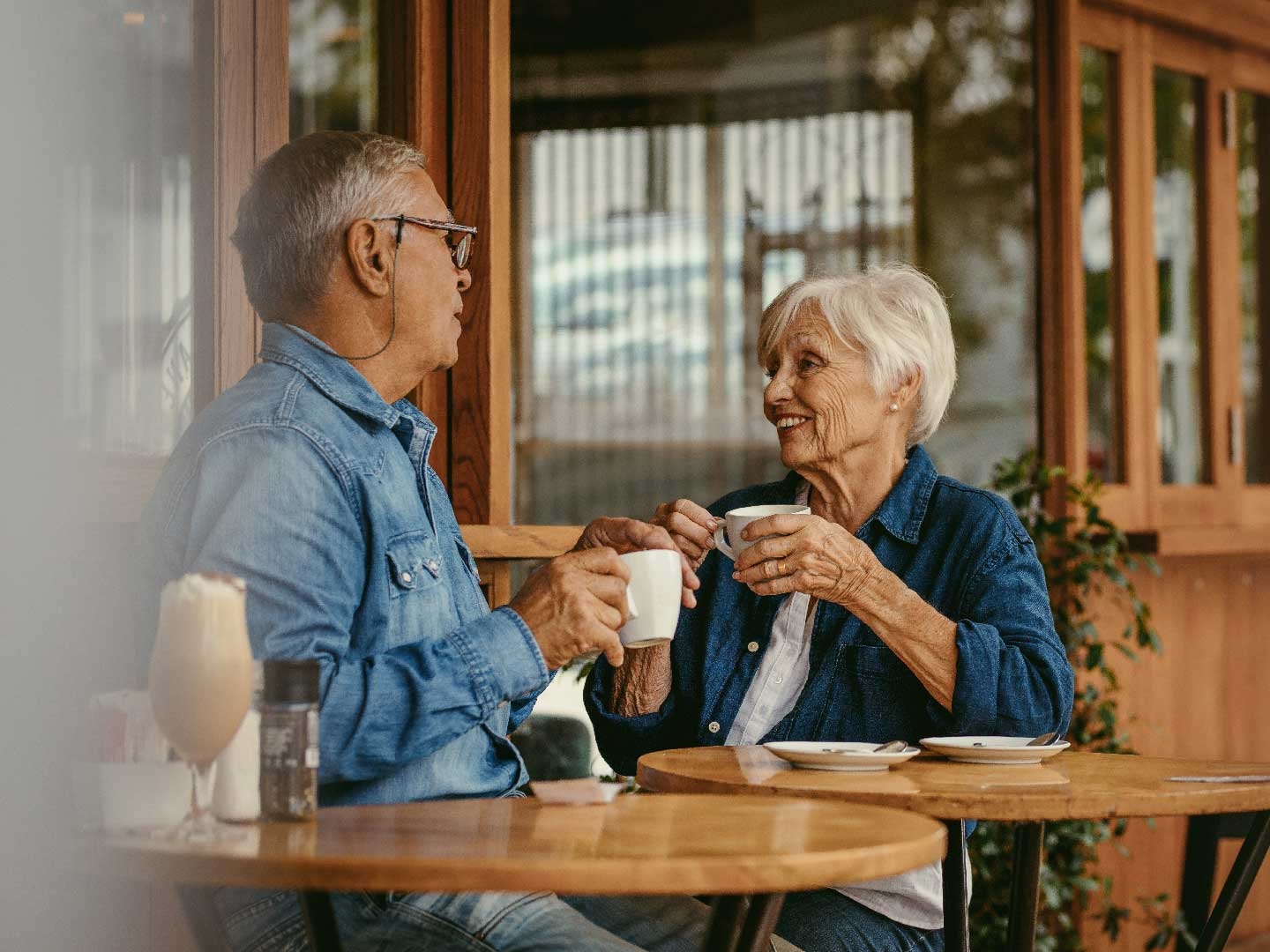 Mature couple sitting chatting over a cuppa outside a cafe