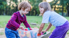 Two kids playing outdoors with building toys