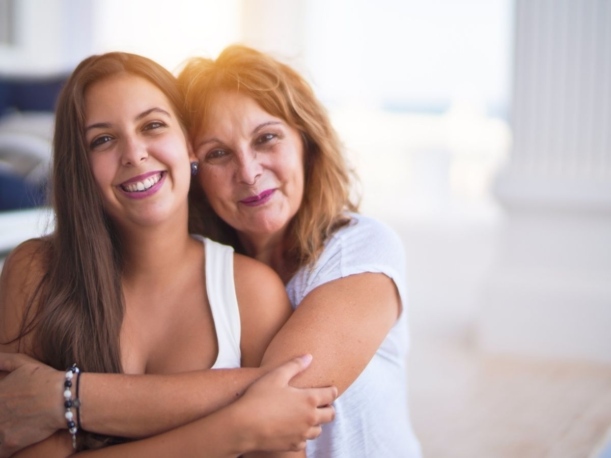 An older woman and her daughter embracing and smiling at the camera