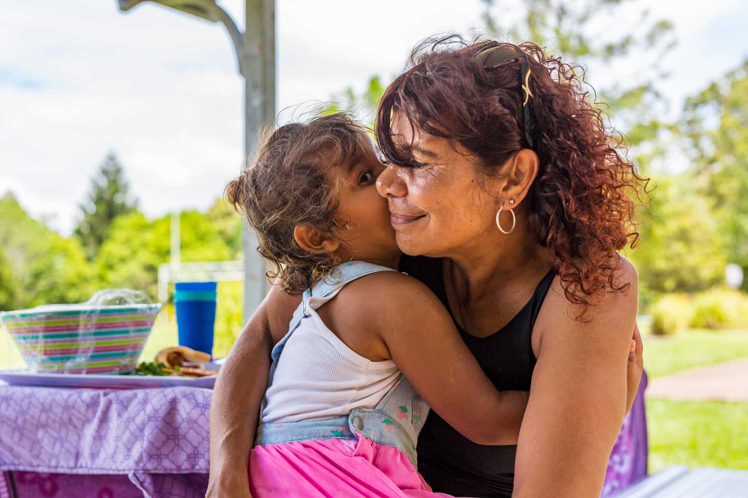 Australian Aboriginal woman giving her granddaughter a hug in the park