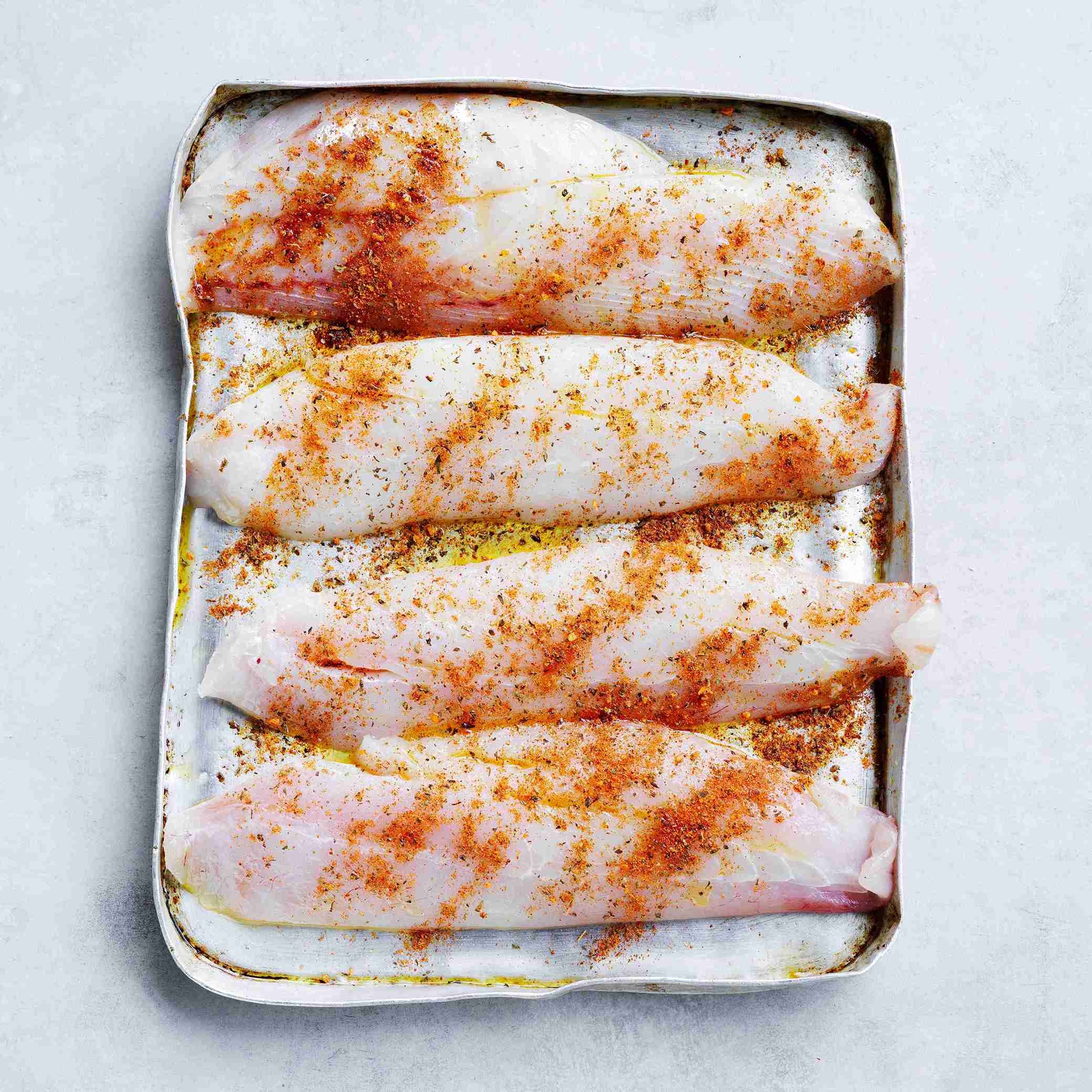 drizzling oil on fish and blending with spices