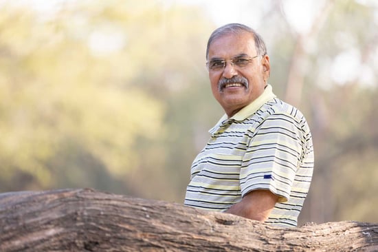 Smiling man with a moustache, striped polo shirt, and glasses, outdoors