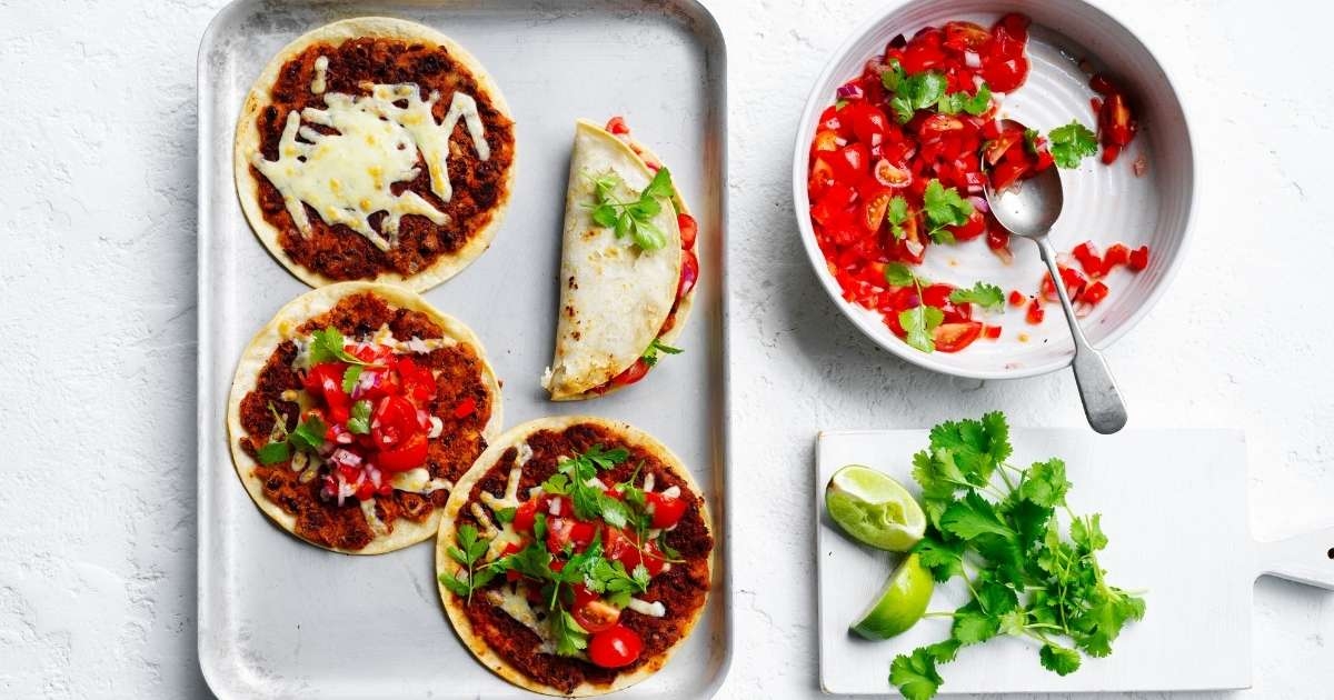 Red kidney bean tacos on tray with tomato salsa and lime next to it