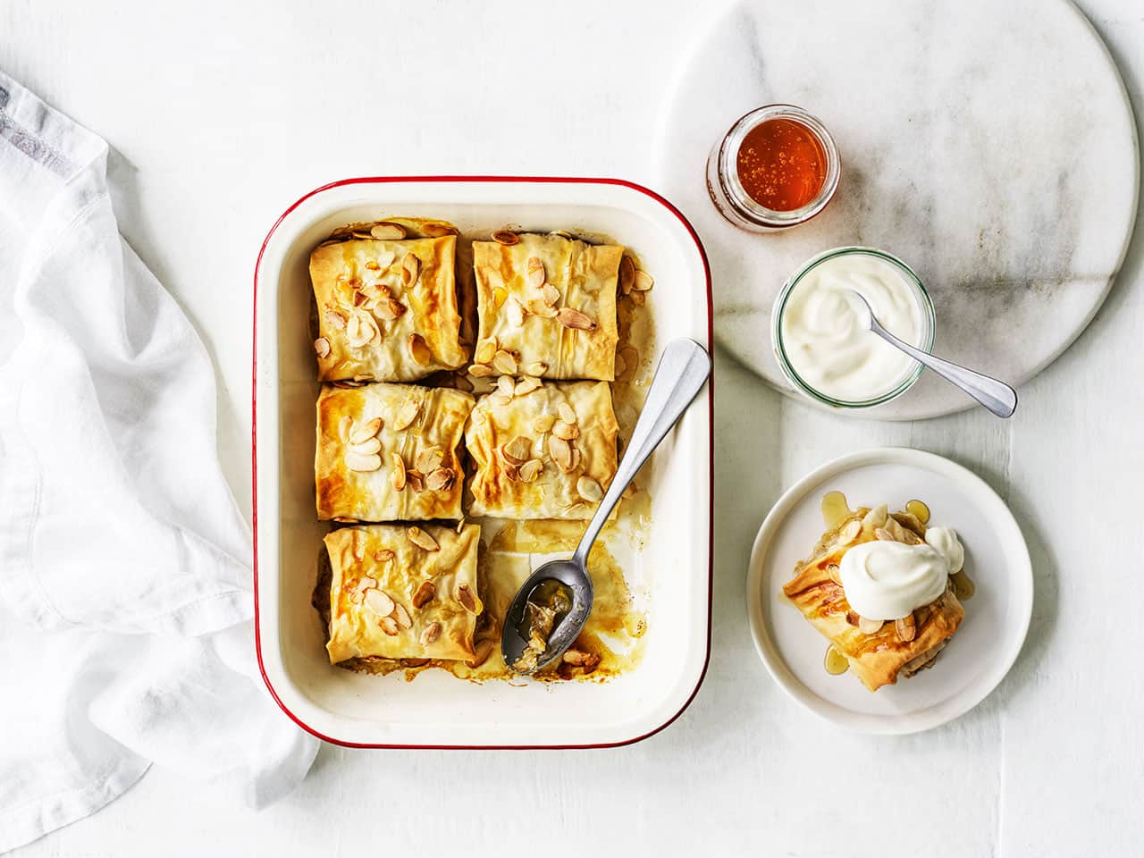 Honey glazed apple dumplings in a tray with side dips on a table