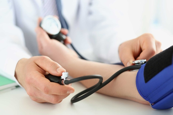 Doctor checking blood pressure of patient in clinic, risk of hypertension
