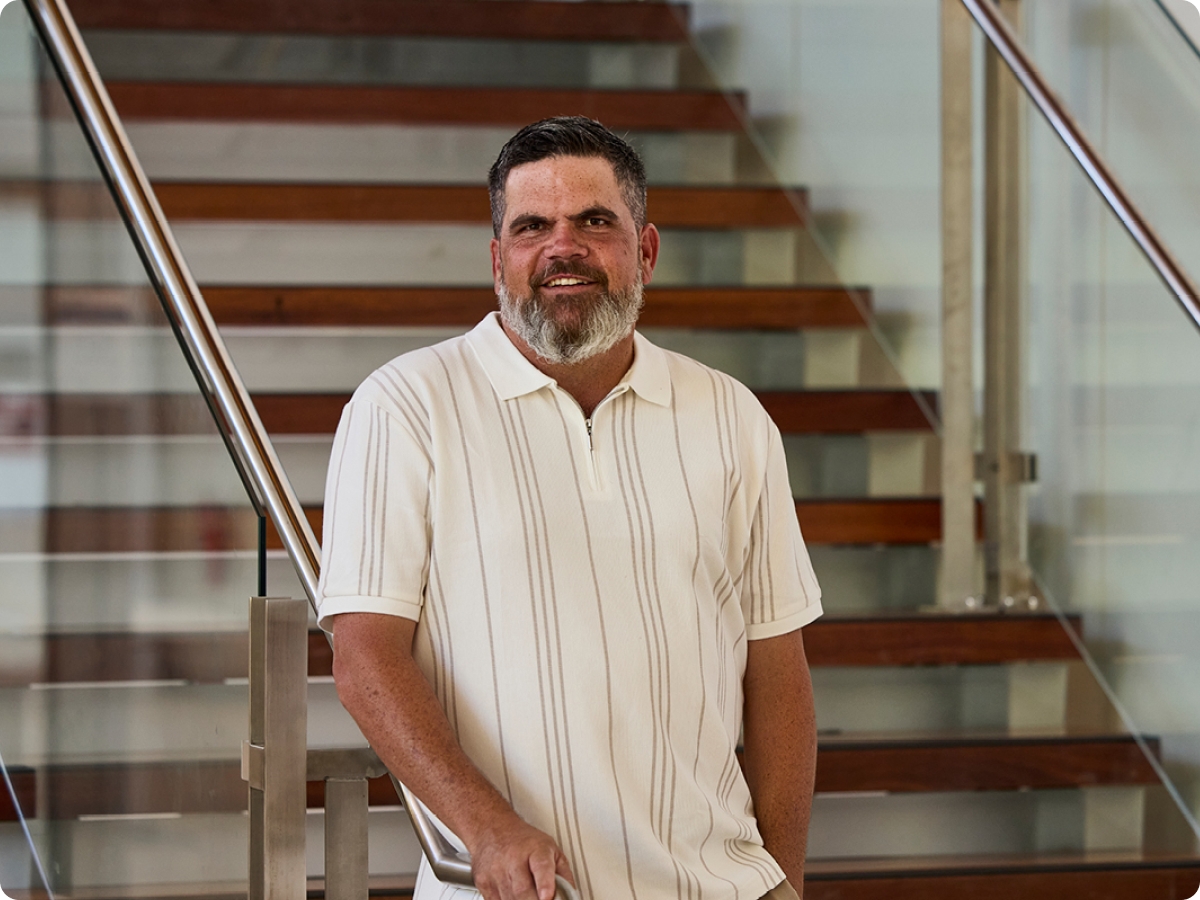 First Nation man, Kieran Bush standing at the bottom of the stairs smiling