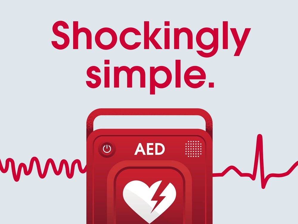 A red automated electronic defibrillator AED alongside a red heartbeat line and the text 'Shockingly Simple'