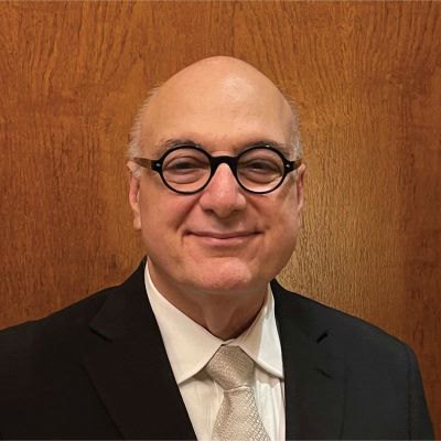 A man in glasses and a suit exudes professionalism and confidence.