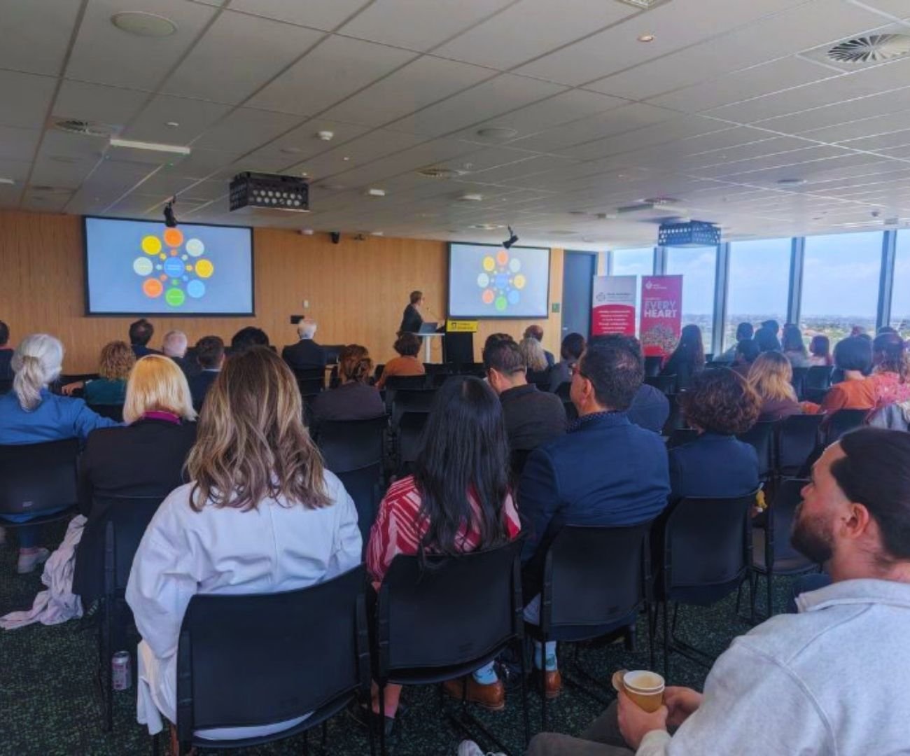 Seated audience listening to speaker and SA CVRN conference event