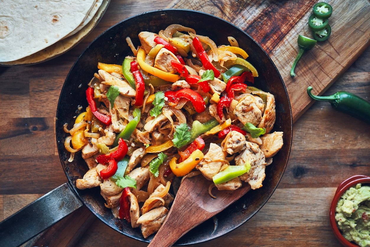 Chicken fajitas with colorful peppers on a sizzling on a hot skillet