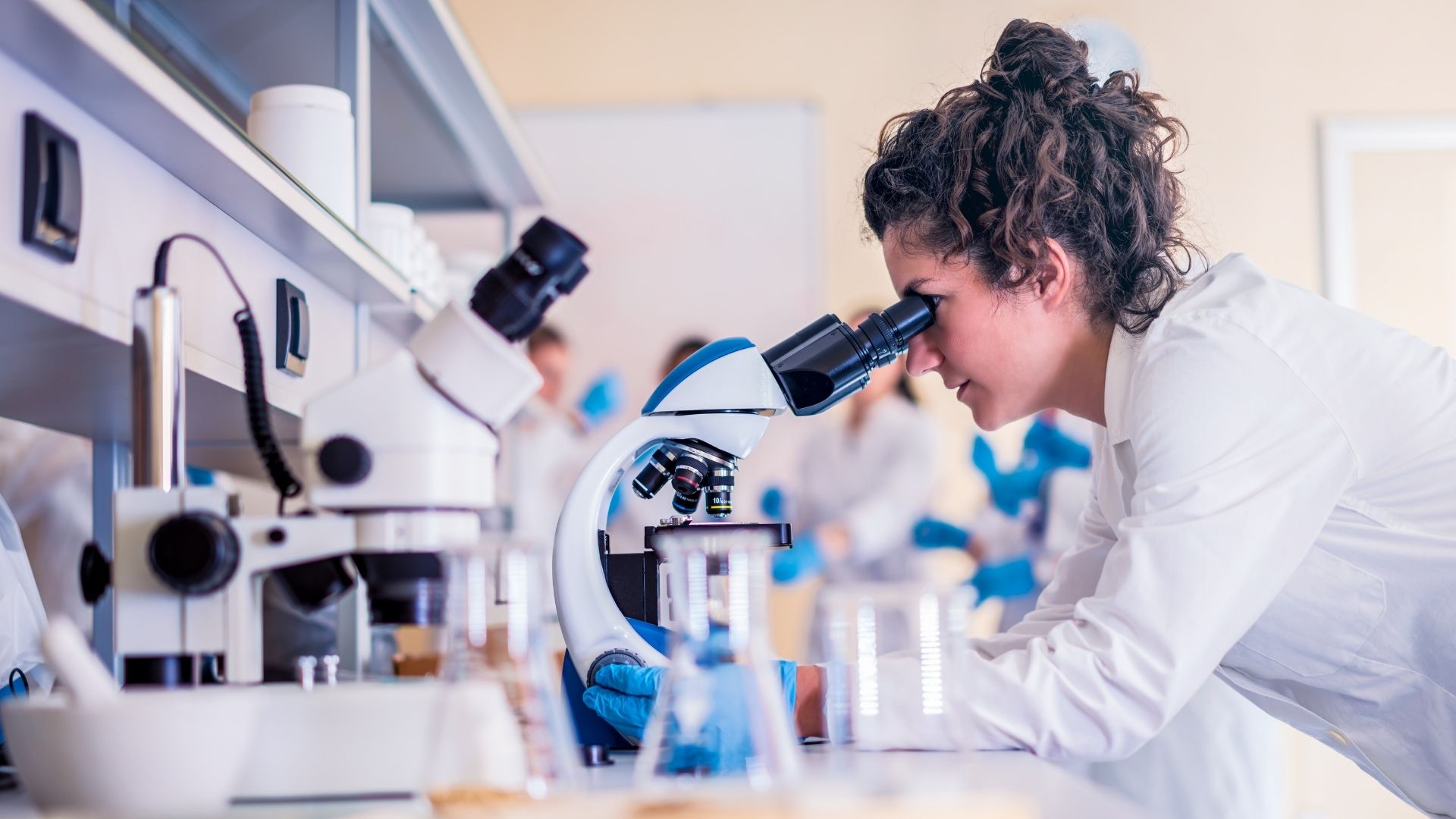 An early career researcher looking through a microscope
