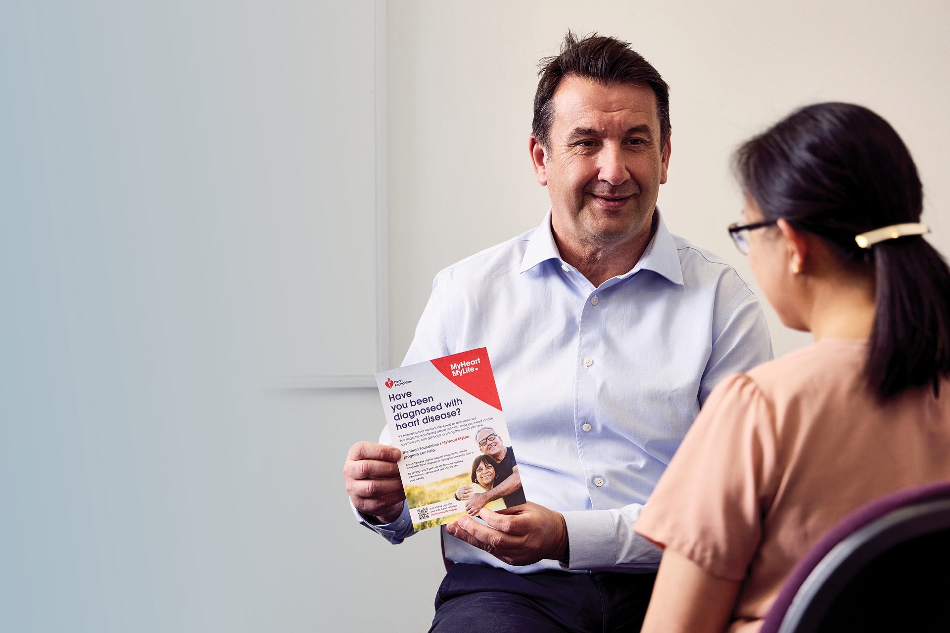 A male doctor showing a patient the MyHeart MyLife patient flyer