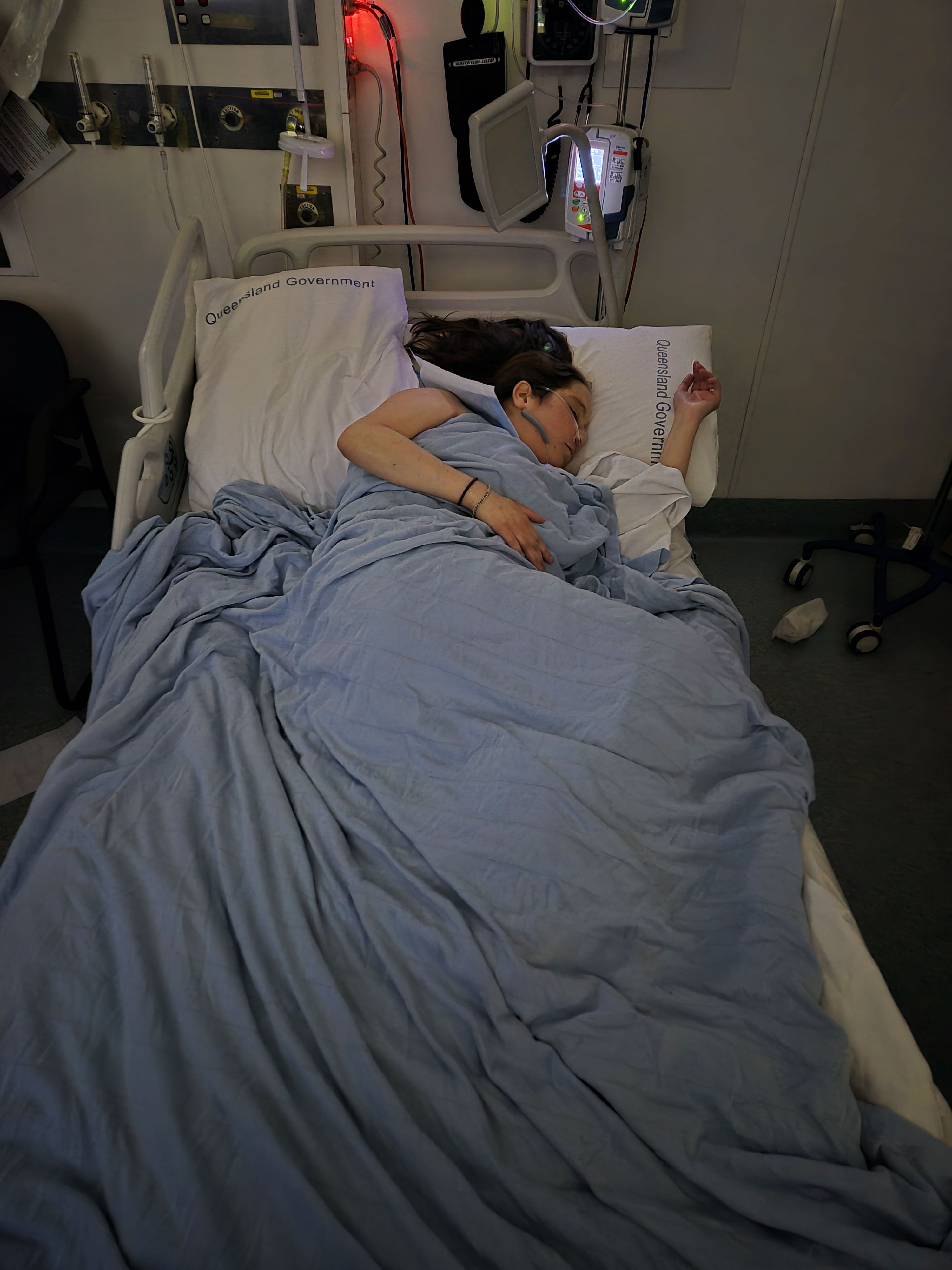 Darkened shot of woman lying sideways in hospital bed