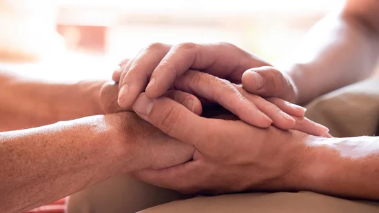 A man's hand stroking the hands of another in support